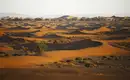 Sahara-Wüstenlandschaft bei Sonnenuntergang Sanddünen der Sahara mit Vegetation unter der Abendsonne.