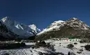 Schneebedeckte Berge und Lodge in Nepal Panorama von schneebedeckten Bergen und einer grünen Lodge in Nepal.