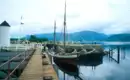 Historisches Schiff im Hafen von Fort William Ein traditionelles Segelschiff liegt im Hafen von Fort William, Schottland, vor Anker. Im Hintergrund sind Berge zu sehen.