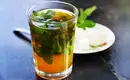Marokkanischer Pfefferminztee - so lecker! Belebender Pfefferminztee im Glas mit frischen Minzblättern und Zuckerwürfeln auf einem Teller daneben.