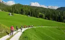 Unterwegs auf guten Pfaden auf der Seiser Alm Gruppe von Wanderern auf einem Pfad in den grünen Hügeln der Dolomiten, umgeben von Berglandschaft.