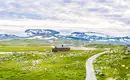 Norwegens majestätische Gletscherlandschaft Ein Holzhaus in Norwegens alpiner Gletscherlandschaft mit schneebedeckten Bergen.