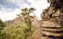 Toller Aussichtspunkt mit Blick in die umliegenden Berge Person wandert auf steinigen Pfaden in den grünen Bergen von La Palma, umgeben von Kiefern.
