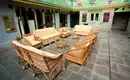 Und jetzt einen Tee in unserer Lodge? Rattanmöbel umgeben einen Tisch in einem Innenhof mit bemalten Wänden in einer Lodge.