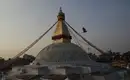 Der goldene Stupa von Bodnath im Abendlicht, umgeben von Gebetsflaggen und einer umherfliegenden Taube.
