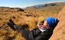 Entspannung in den Drakensbergen Person entspannt auf einem Felsen in der Berglandschaft der Drakensberge mit weitem Ausblick.