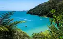Atemberaubende Küste im Abel Tasman Nationalpark Türkisblaues Meer, üppiger Regenwald und Boote im Abel Tasman Nationalpark, Neuseeland.