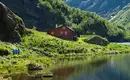 Idylle am norwegischen Fjord Rotes Haus am Seeufer in Norwegens Fjordlandschaft.