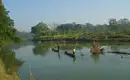 Einbaumfahrt im Chitwan-Nationalpark Zwei Einbäume auf einem Fluss im Chitwan-Nationalpark, umgeben von üppiger Vegetation.