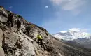 Ab und an kommen die Hände zum Einsatz... Wanderer auf felsigem Pfad mit schneebedeckten Bergen im Hintergrund.