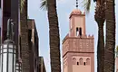 Marrakech Tour – Koutoubia-Moschee Koutoubia-Moschee in Marrakech, umgeben von Palmen, mit einem klaren Himmel im Hintergrund.