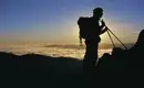Wanderer bei Sonnenuntergang in Neuseeland Silhouette eines Wanderers mit Rucksack und Wanderstöcken vor einem spektakulären Sonnenuntergang in Berglandschaft.