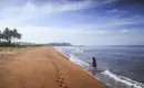 Strandspaziergang entlang der endlosen Küste Person geht am ruhigen Sandstrand in Sri Lanka entlang, mit Palmen im Hintergrund.
