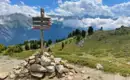 Wanderwegweiser in den Alpen Holzwegweiser auf einem alpinen Wanderpfad mit Berglandschaft im Hintergrund.
