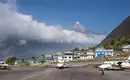 Flughafen in Lukla mit Bergpanorama Flugzeuge am Flughafen Lukla, umgeben von Bergen und bewölktem Himmel in Nepal.