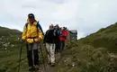 Unsere Wandergruppe entlang des Wegs Gruppe von Wanderern in den Alpen, Alpenhütte im Hintergrund.