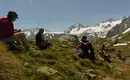 Verdiente Mittagspause mit Blick in die umliegenden 3.000er Wanderer genießen die Aussicht auf schneebedeckte Berge in den Stubaier Alpen. Eine Gruppe sitzt auf der Wiese.