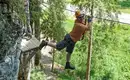 Akrobatik am Stahlseil - sieht schon gut aus:-) Person mit Sicherheitsausrüstung beim Klettersteig auf einer Seilbrücke im Wald.