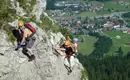 Was für ein fantastischer Tiefblick ins Tal Drei Kletterer an einem felsigen Klettersteig mit Blick auf ein Tal in den Alpen.