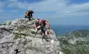 Der Abstieg erfolgt über die Leiter Gruppe von Kletterern auf einem Klettersteig in alpiner Landschaft.