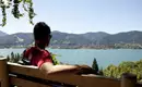 Atemberaubender Blick auf den Tegernsee Person sitzt auf einer Bank mit Blick auf den Tegernsee und umliegende Berge.