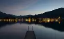 Lichter am Tegernsee in der Abenddämmerung Nächtliche Ansicht von Tegernsee mit Lichtern und Steg am Wasser.