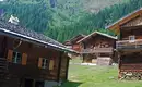 Berghütten im alpinen Dorf Holzhütten in alpiner Landschaft mit grünen Bergen im Hintergrund.