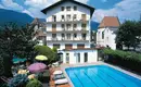 Eine unserer Unterkünfte mit Pool in der Nähe von Meran Ein Hotel mit Pool, umgeben von Bergen, unter blauem Himmel.