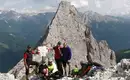 Kurze Verschnaufpause auf dem Weg zum nächsten Klettersteig Gruppe von Kletterern auf einem Berggipfel mit felsiger Landschaft und Bergen, im Hintergrund der Rosengarten.