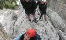 Was für ein Tiefblick von unserem Klettersteig aus! Drei Personen gehen gesichert einen Klettersteig in den Dolomiten am Fels.