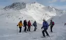 Kurze Technikbesprechung mit dem Bergführer Gruppe von Skifahrern genießt den Tiefschnee im Stubaier Skigebiet vor einer Gebirgskulisse.