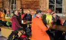 Gemütliche Runde beim Skitechnik-Kurs - bei der verdienten Mittagsjause Gruppe bei einer Pause auf den Holzbänken, sonniger Wintertag im Stubai.