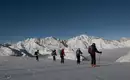 Und alle im Gleichschwung! Teilnehmer einer Skitour im Stubaital, umgeben von schneebedeckten Alpen.