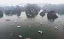 Boote in der Halong-Bucht Luftaufnahme vieler Boote in der Halong-Bucht, umgeben von markanten Karstfelsen und trübem Himmel.