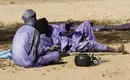 Nomaden in der Sahara-Ruhepause Zwei Personen in traditionellen Gewändern ruhen im Schatten in der Sahara.