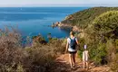 Meist laufen wir über gute Wanderwege - toller Meerblick inklusive Eine Wandererin mit Kind auf einem Küstenpfad auf Korsika mit Blick aufs Meer.