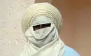 Traditioneller Tuareg mit Gesichtstuch Eine Person in traditioneller Tuareg-Kleidung mit hellem Gesichtstuch vor einer Steinwand. Sahara-Reisen.