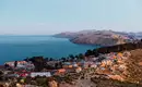 Blick auf Isla del Sol und den Titicacasee Panoramablick auf ein Dorf auf der Isla del Sol am Titicacasee, umgeben von Hügeln unter klarem Himmel.