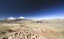 Majestätische Vulkane in Atacama Blick auf zwei schneebedeckte Vulkane in einer weiten Wüstenlandschaft unter klarem Himmel.