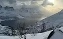 Verschneite Berge und Fjord unter bewölktem Himmel auf den Lofoten.