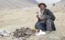 Pilger mit Gebetsmühle bei der Umrundung des Kailash Ein Bergsteiger mit Gebetsmühle und traditioneller Kleidung in der Himalaya-Landschaft Tibets.