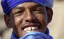 Tuareg in seiner traditioneller Kleidung Ein junger Tuareg mit blauem Turban lächelt in die Kamera.