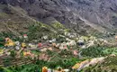 Panorama von La Gomera Blick auf ein Dorf in La Gomera mit Bergen im Hintergrund und Palmen im Tal.