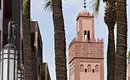 Marrakech Tour – Koutoubia-Moschee Koutoubia-Moschee in Marrakech, umgeben von Palmen, mit einem klaren Himmel im Hintergrund.