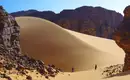 Sahara-Dünenlandschaft in Algerien Zwei Personen erkunden die Sahara zwischen Felsen und Sanddünen.