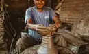 Töpferkunst in Nepals Dörfern Ein lächelnder Mann töpfert in einer traditionellen Werkstatt in Nepal.