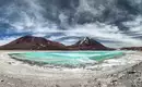 Lagune in der Atacama-Wüste Bizarre Landschaft mit grünblauer Lagune in einer Wüstenregion. Im Hintergrund erheben sich hohe Berge unter dramatischem Himmel.