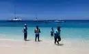 Strandabenteuer auf den Seychellen Menschen am Strand der Seychellen vor klarem, blauem Wasser mit Booten.