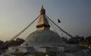 Der goldene Stupa von Bodnath im Abendlicht, umgeben von Gebetsflaggen und einer umherfliegenden Taube.