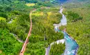 Norwegische Landschaft mit endlosen Wäldern und türkisgrünen Flüssen Bahnstrecke durch grünes Tal mit Fluss in Norwegen, umgeben von Wald.